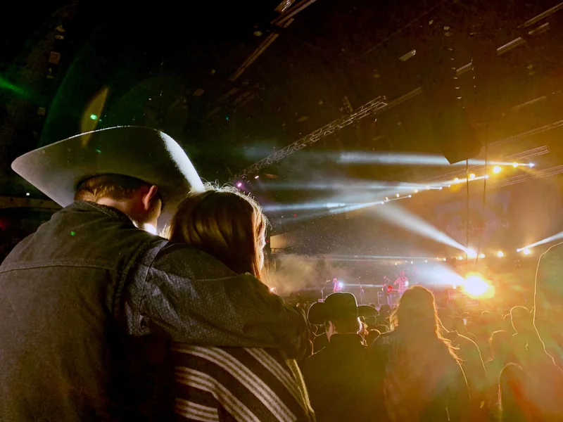 Cowboy hats and a couple in a close-up country concert crowd