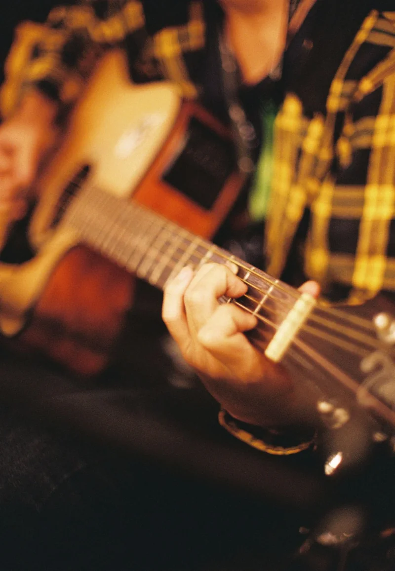Hands playing an acoustic guitar in warm light