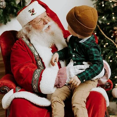 Santa with a child beside a Christmas tree