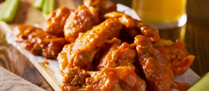 Sauced chicken wings with fresh vegetables and dip